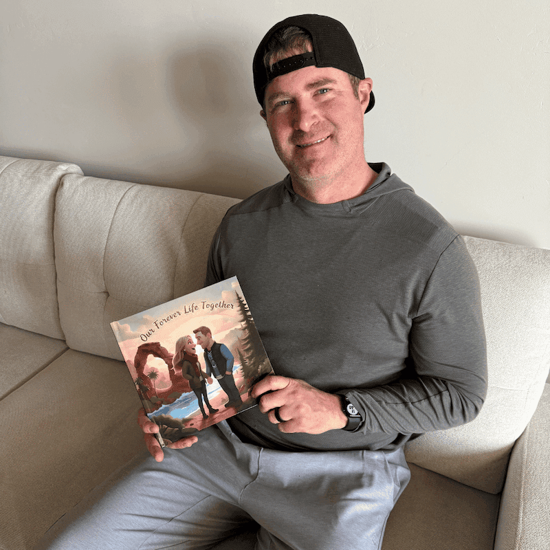 A man sitting on a sofa holding his personalized Love Tales book